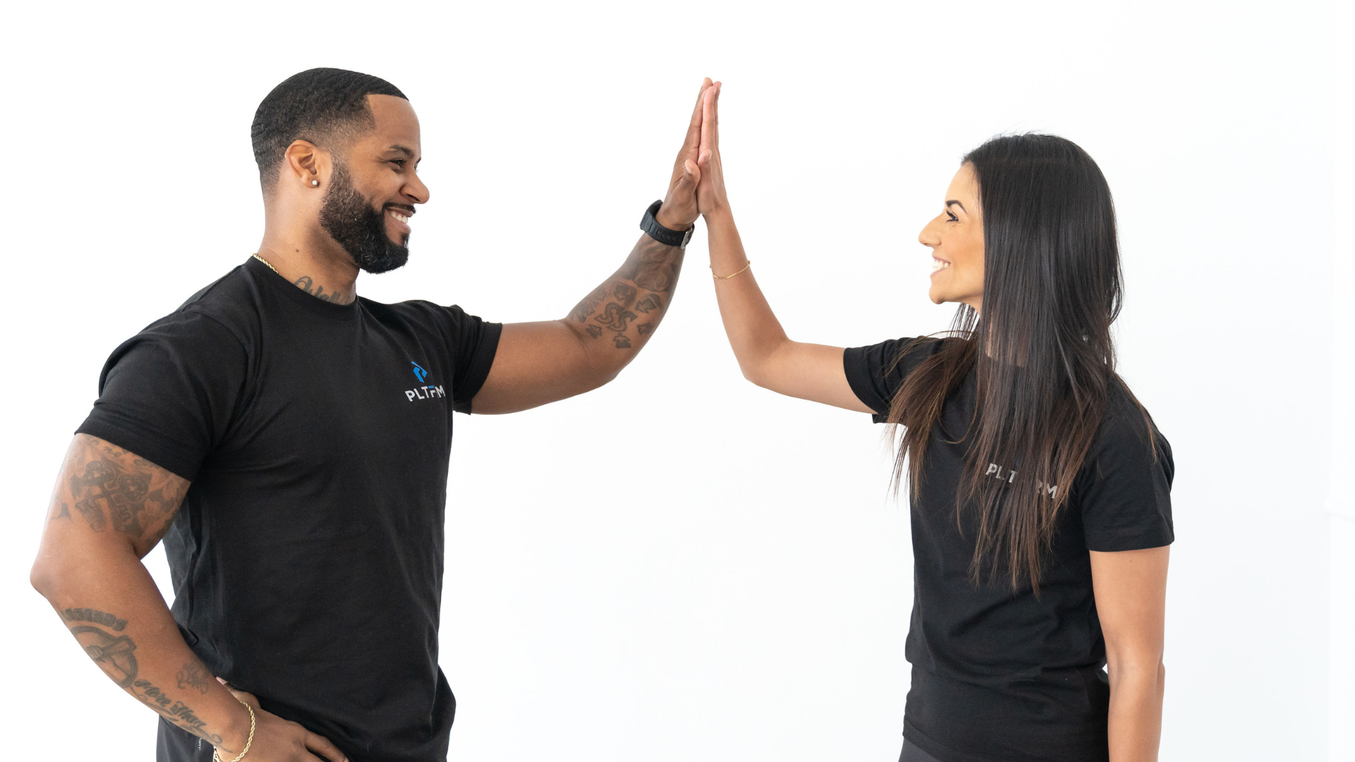 Two personal trainers wearing black t-shirts with the PLTFRM logo.